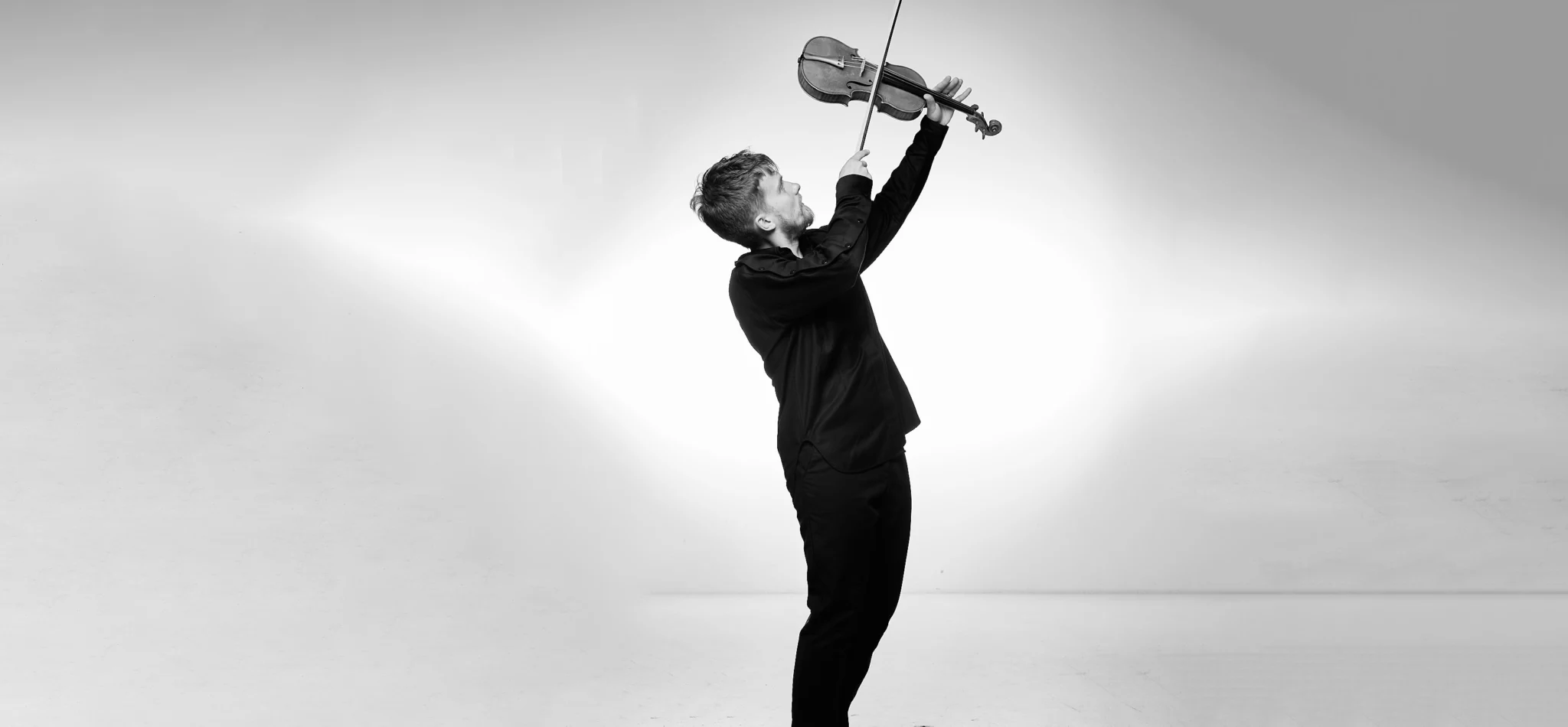Dmitry Smirnov holding the violin high above his head, black and white