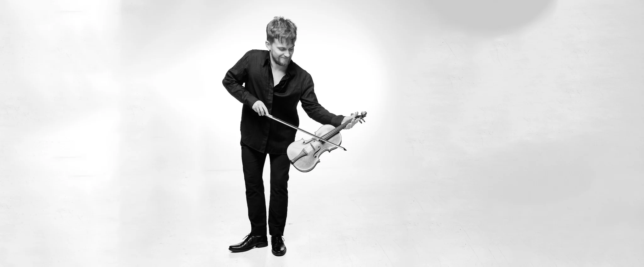 Dmitry Smirnov bowing with violin, black and white. Photo: Matthias Müller